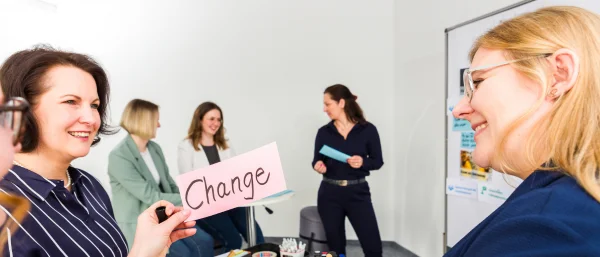 Die Trainerinnen von Carpe Verba stehen vor einer Pinnwand und sind im Austausch über das Thema "Change: Transformation gestalten und begleiten".