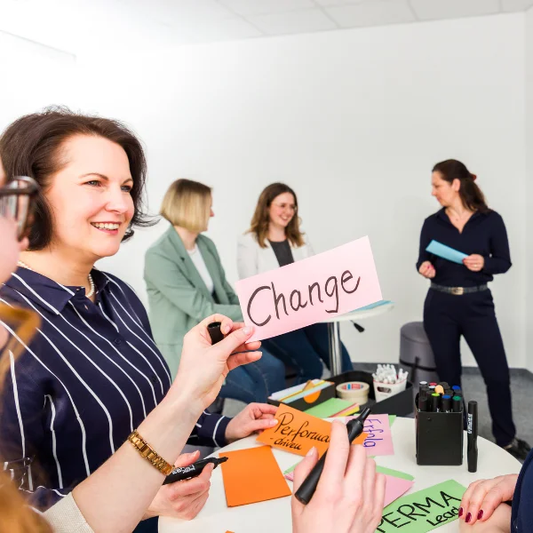 Die Trainerinnen von Carpe Verba stehen vor einer Pinnwand und sind im Austausch über das Thema "Change: Transformation gestalten und begleiten".