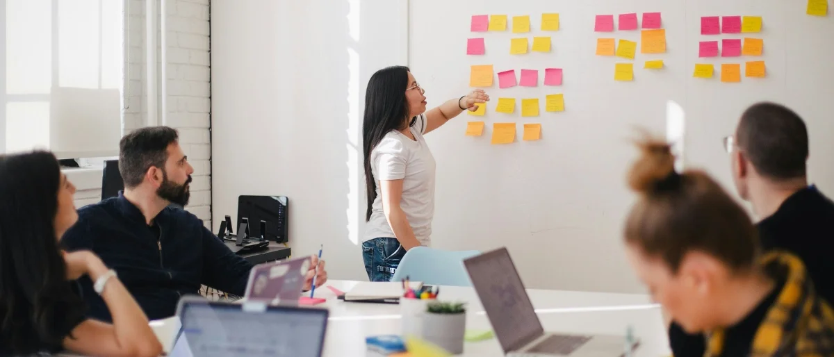 Mehrere Personen diskutieren im Prozess der Entscheidungsfindung vor einer Wand mit Post-Its mit verschiedenen Entscheidungsmöglichkeiten