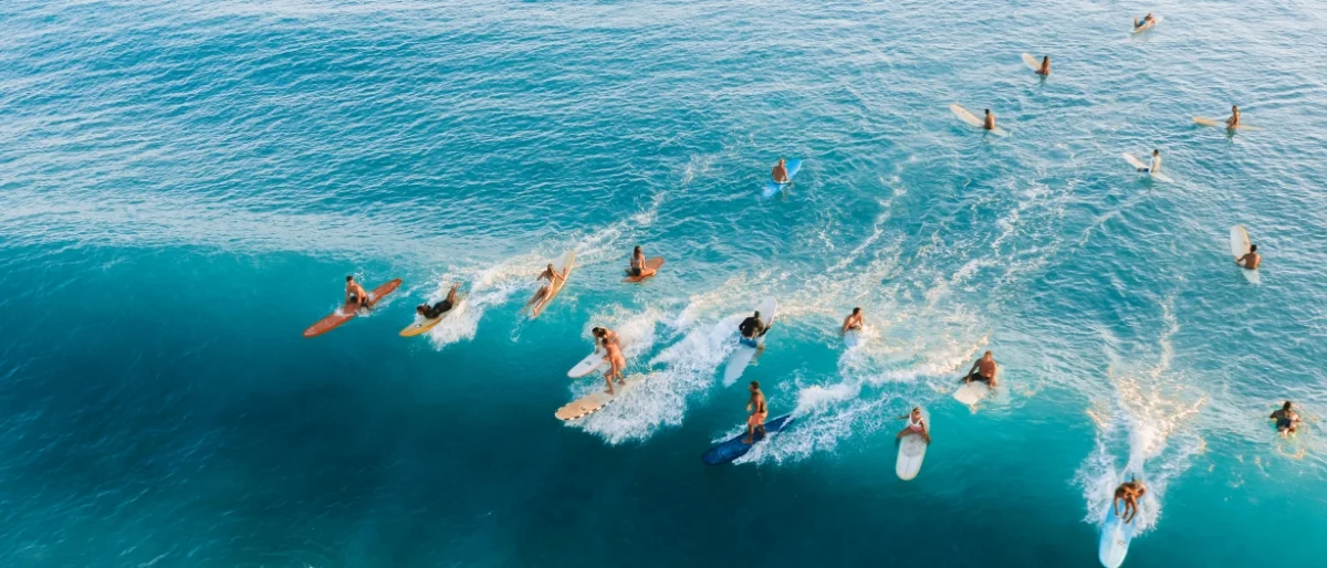Mehrere Surfer auf blauem Wasser stehen symbolisch für den Schwung und das Meistern von Herausforderungen durch erfolgreiche Führung in Change und Transformation.