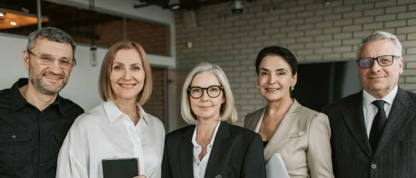 Eine Gruppe von fünf Führungskräften blickt in die Kamera