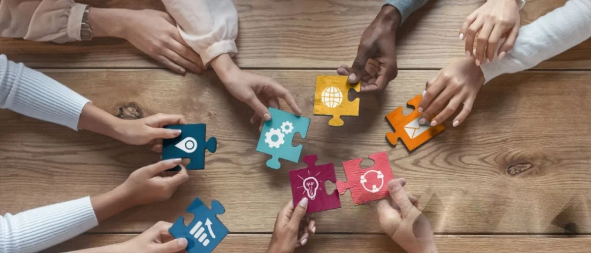 Hände fügen Puzzle zusammen als Symbol für Onboarding Führungskraft im Team