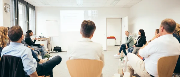 Eine Gruppe von Menschen sitzt in einem Stuhlkreis tauscht sich zum Thema Führungskreisentwicklung aus.