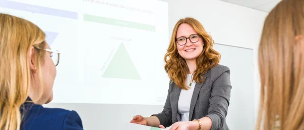 Eine Trainerin von Carpe Verba hält einen Vortrag und interagiert dabei mit den Zuhörenden.