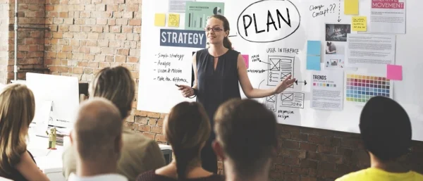 Frau präsentiert eine kreative Strategievorstellung vor einem Team – Symbol für Innovation, kreative Prozesse und Zusammenarbeit in Teams.