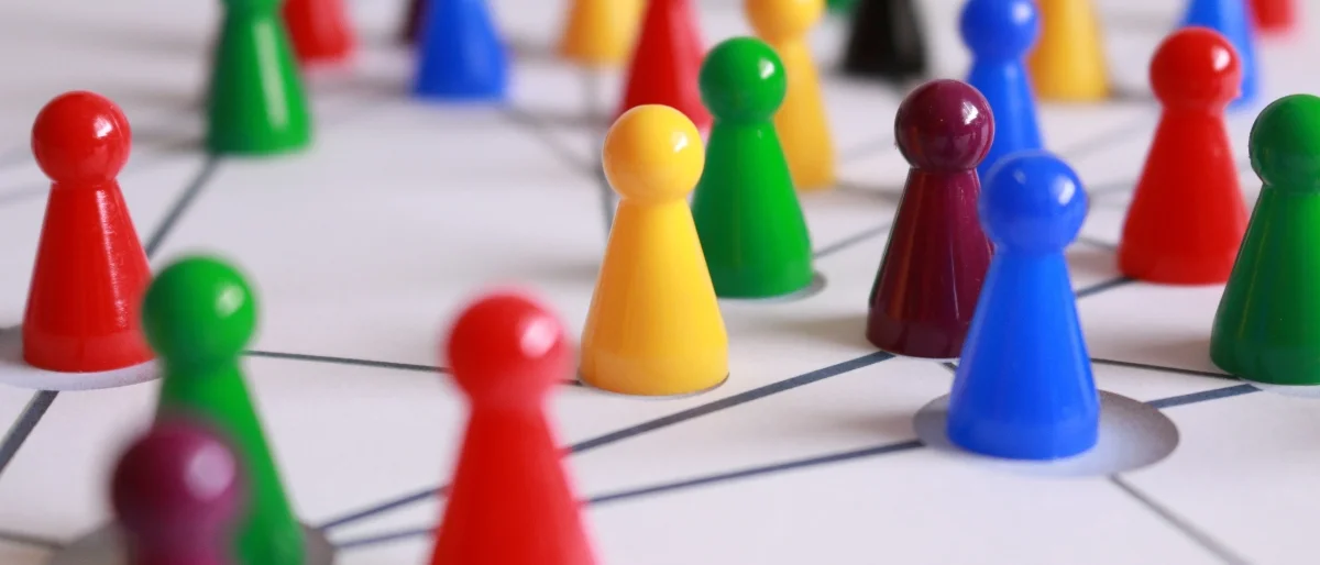 Bunte Spielfiguren, die durch Linien verbunden sind, symbolisieren kreatives Teamwork, Innovationskraft und Zusammenarbeit in dynamischen Prozessen.