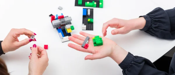 Zwei Personen halten Legosteine in der Hand. Das Bild steht symbolisch für den Workshop "Kreativität und Inspiration für innovative Teams".