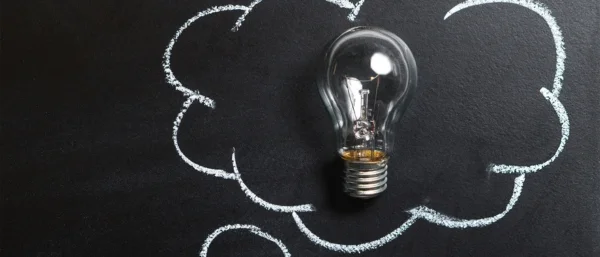 Eine Glühbirne liegt auf einer Tafel, in der eine Wolke mit Kreide gezeichnet ist – sie symbolisiert eine Gedankenblase. Die Glühbirne steht als Sinnbild für Ideen, Kreativität und neue Impulse. Das Bild transportiert den Moment der Inspiration und ermutigt dazu, querzudenken, Altes zu hinterfragen und mutig neue Wege zu gehen.