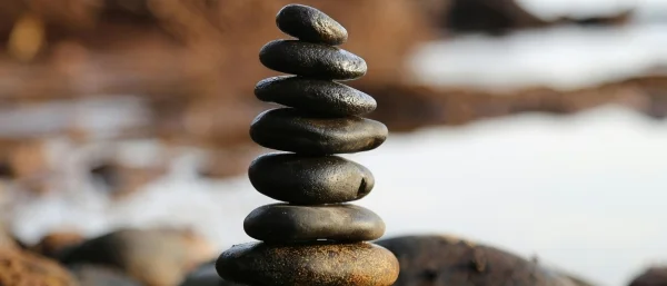 Gestapelte Steine in Balance als Symbol für eine souveränes Führen ohne Stress und in Balance nach einem Kurzimpuls von Carpe verba!