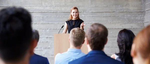 Frau hält motivierenden Vortrag als Symbol eines Impulsvortrags Positive Leadership