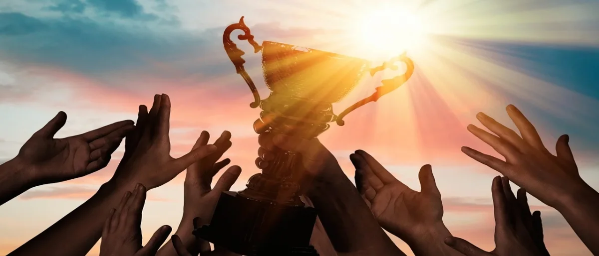 Sportler heben einen Pokal als Symbol für Impulsvortrag zu Positive Leadership