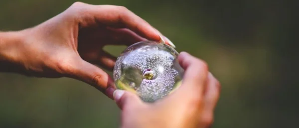 Zwei Hände halten eine Glaskugel, die symbolisch für die gezieltes Fördern und Umsetzen von Innovation in Führung steht.