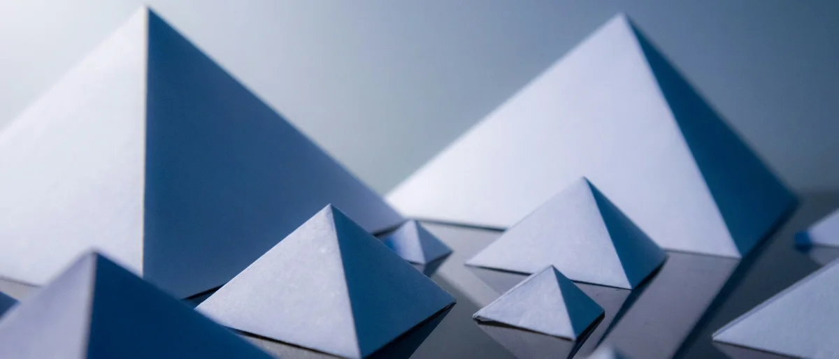 Pyramidale Formen auf dunklem Grund repräsentieren pyramidales Denken, das im Training erlernt werden kann.