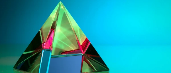 Eine bunte Pyramide steht vor einem blauen Hintergrund. Dies steht symbolisch für pyramidale Kommunikation.