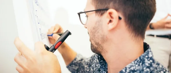 Mann schreibt auf Flipchart als Symbol für Team Workshop gemeinsame Ausrichtung und Selbstorganisation