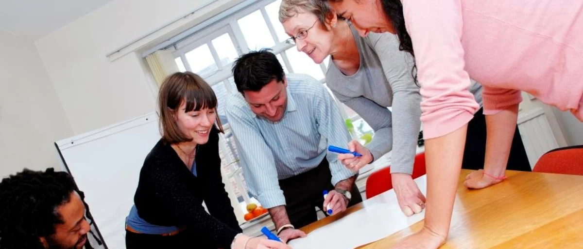 5 KollegInnen arbeiten gemeinsam als Symbol für gute Teamzusammenarbeit