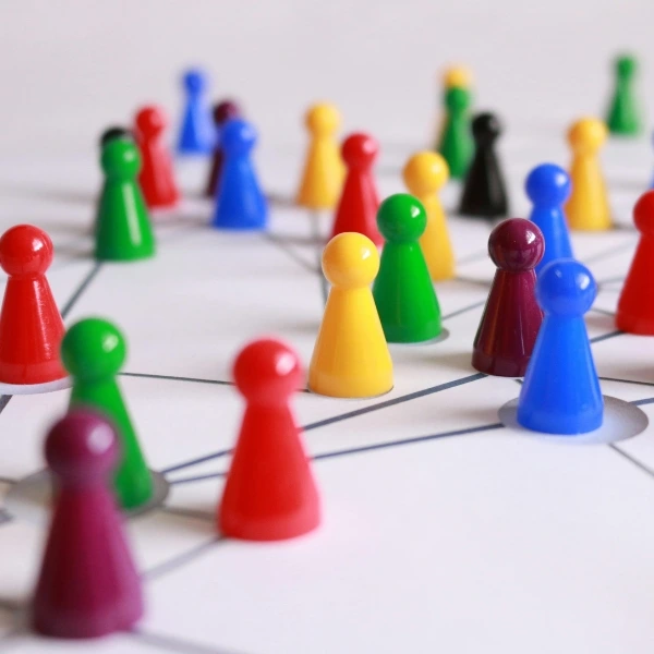 Bunte Spielfiguren sind durch Linien verbunden und symbolisieren ein starkes Netzwerk, Teamarbeit und systemisches Denken in Organisationen.