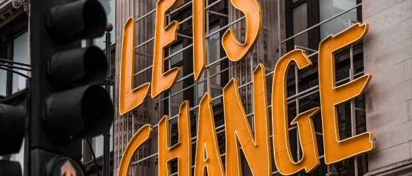 An einer Hauswand befestogter Schriftzug "Lets Change" verdeutlicht die Relevanz von Gestaltung und Begleitung von Transformationsprozessen