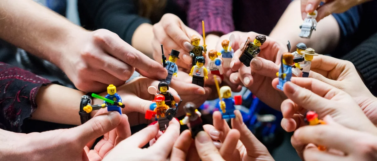 Hände mit Legofiguren als Symbol für Teamworkshop