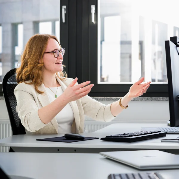 Marlies Voggenreiter - Trainerin bei Carpe Verba - sitzt vor einem Bildschirm und ist im Austausch mit Teilnehmenden eines virtuellen Meetings.