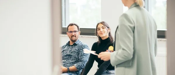 Zwei duale Studierende im Bachelorstudiengang Personalmanagement sitzen und hören gespannt der Expertin Jana Schmid von Carpe verba! zu