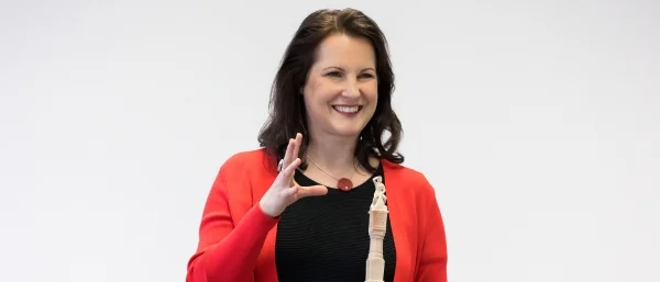 Frau präsentiert mit einem Lächeln eine Figur – Symbol für Storytelling, emotionale Kommunikation und wirkungsvolle Präsentationstechniken.