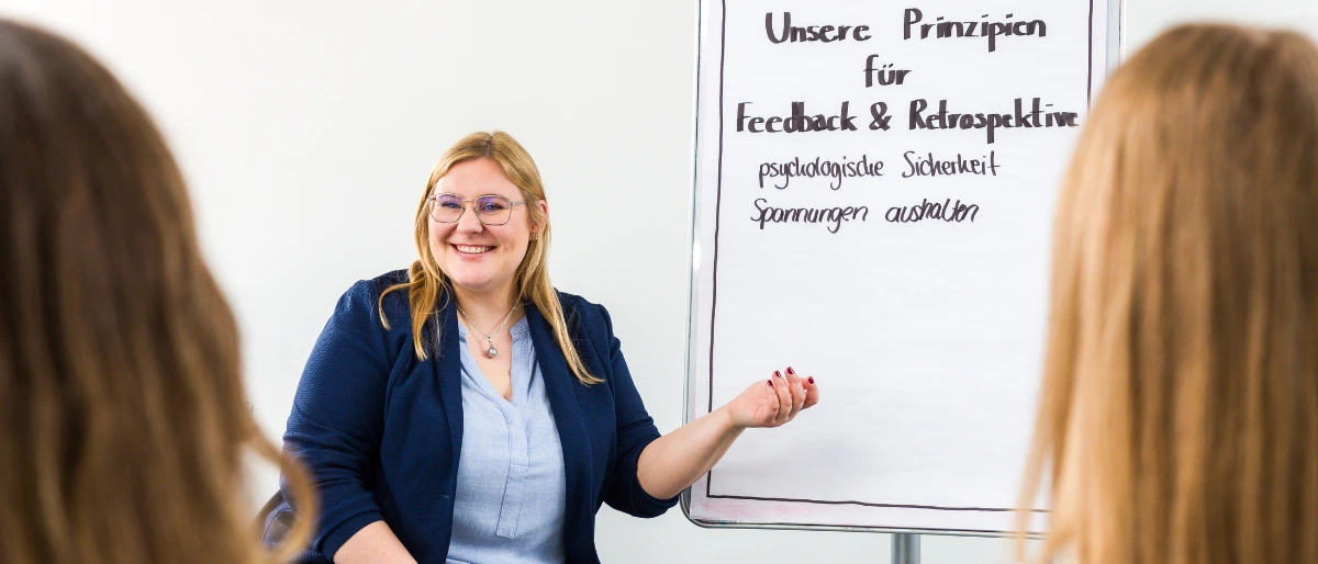 Bettina Golba - Trainerin bei Carpe Verba - sitzt vor einem Flipchart und moderiert zum Thema "Feedback wirkungsvoll - Let's Feedforward".