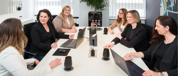 Das Team von Carpe verba! aus Regensburg sitzt an einem Konferenztisch und spricht miteinander – eine Szene aus der Arbeit in der Teamentwicklung und Organisationsentwicklung.
