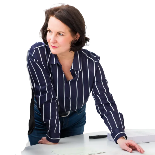 Hanne Philipp lehnt sich in dynamischer Haltung über einen Tisch und blickt fokussiert zur Seite. Sie gestaltet moderne Personalentwicklung und Organisationsentwicklung in Regensburg