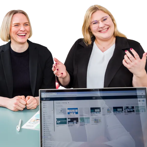 Jana Schmid und Bettina Golba sitzen an einem Tisch und führen ein Gespräch. Im Vordergrund ist ein Laptop mit einer geöffneten Präsentation zu sehen. Das Bild zeigt eine Szene aus der Arbeit von Carpe verba! im Bereich Personalentwicklung und Organisationsentwicklung in Regensburg.